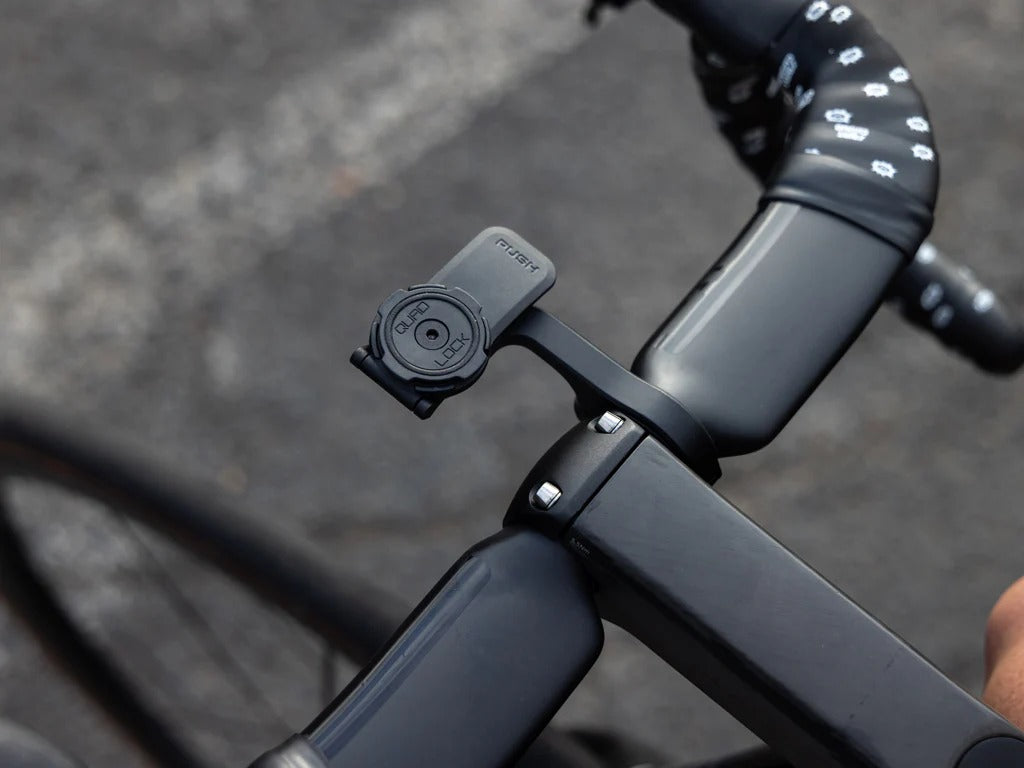 Quad Lock Out Front Mount mounted on road bike handlebar against a blurred road background