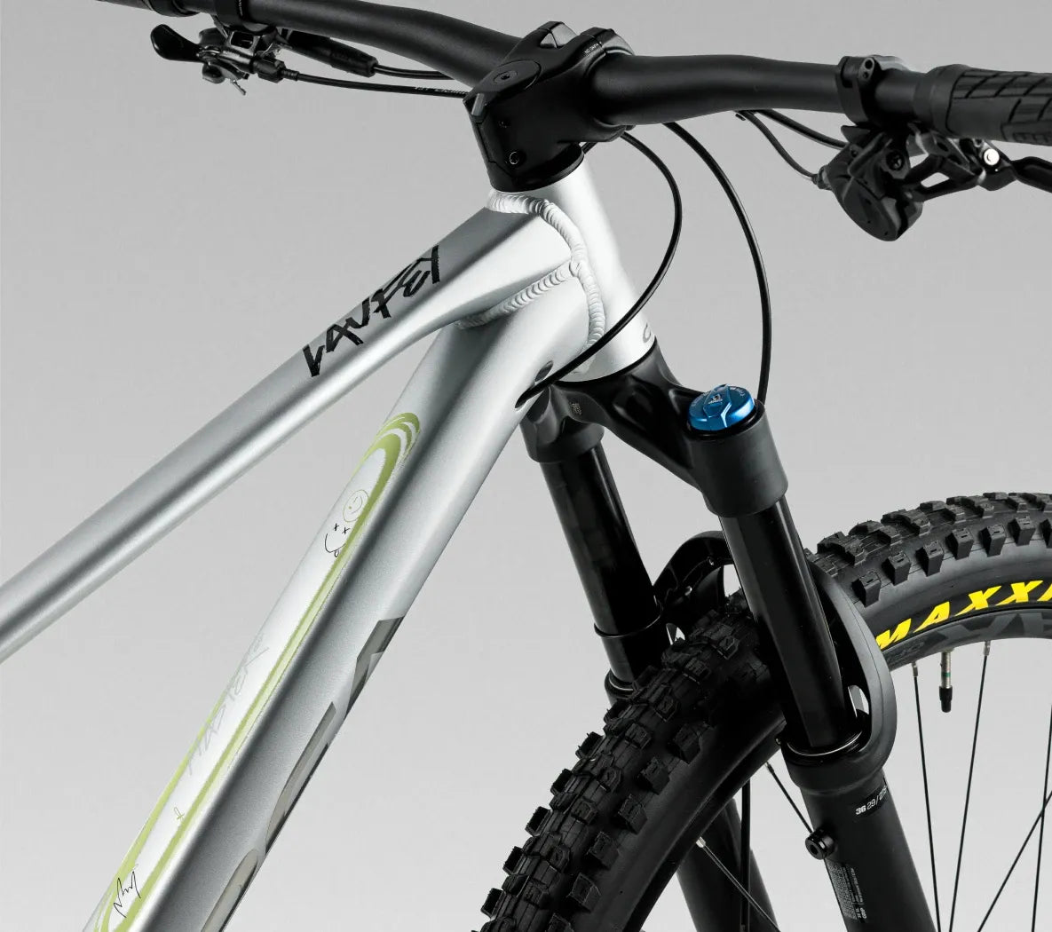 Close-up of a mountain bike with a silver frame and black components on a gray background
