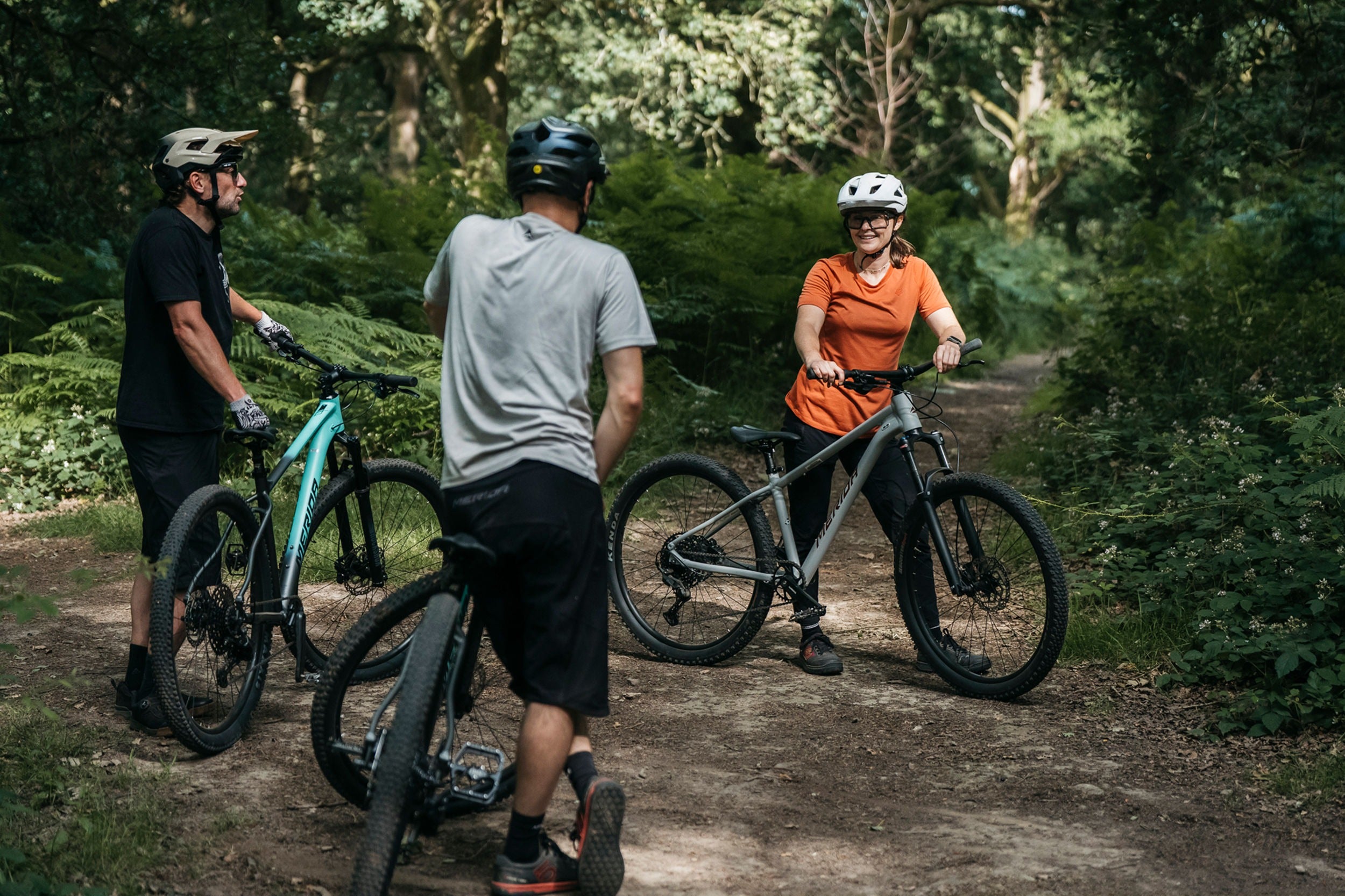 Three people with electric bikes on a forest trail