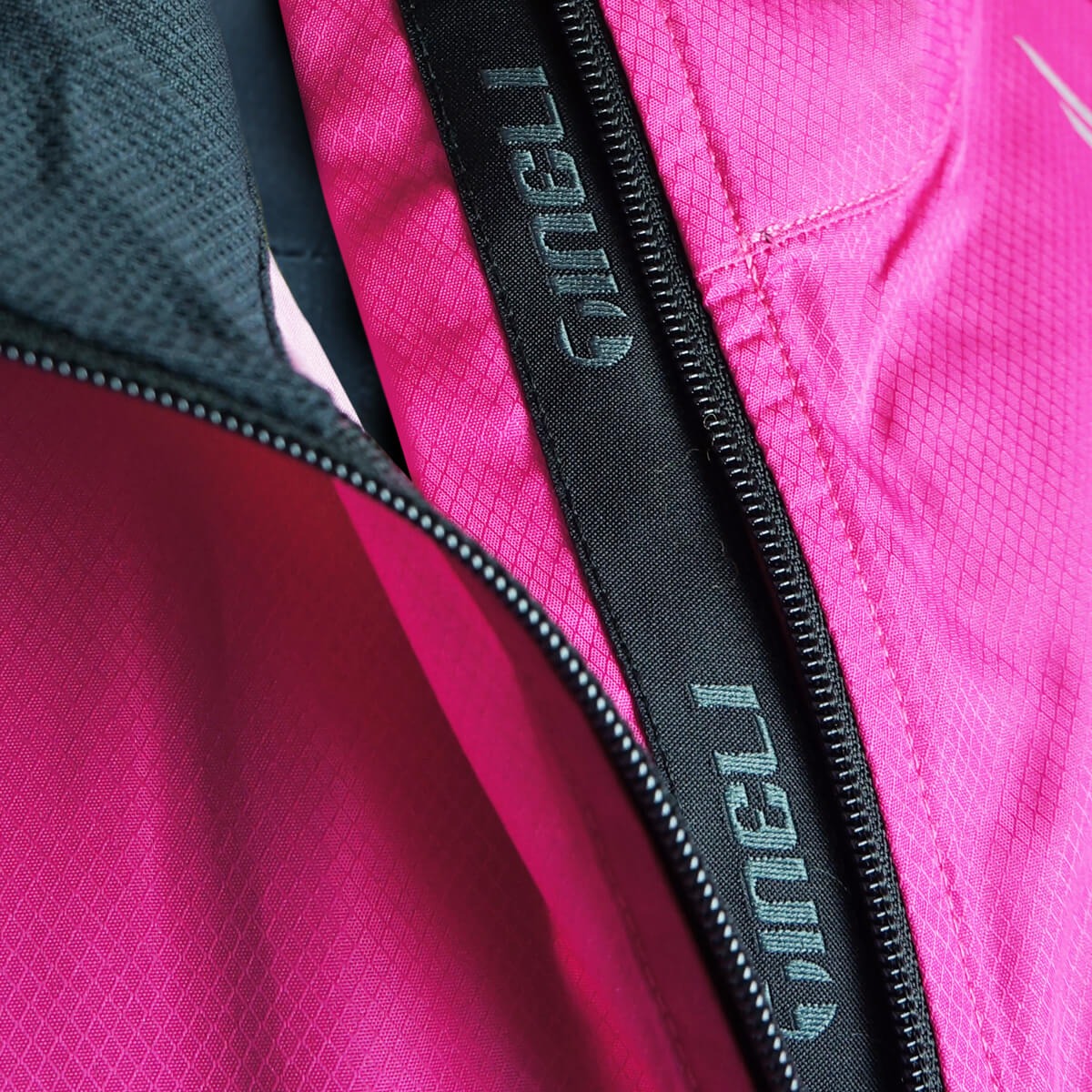 Close-up of a pink jacket with a black zipper and 'Tineli' branding.
