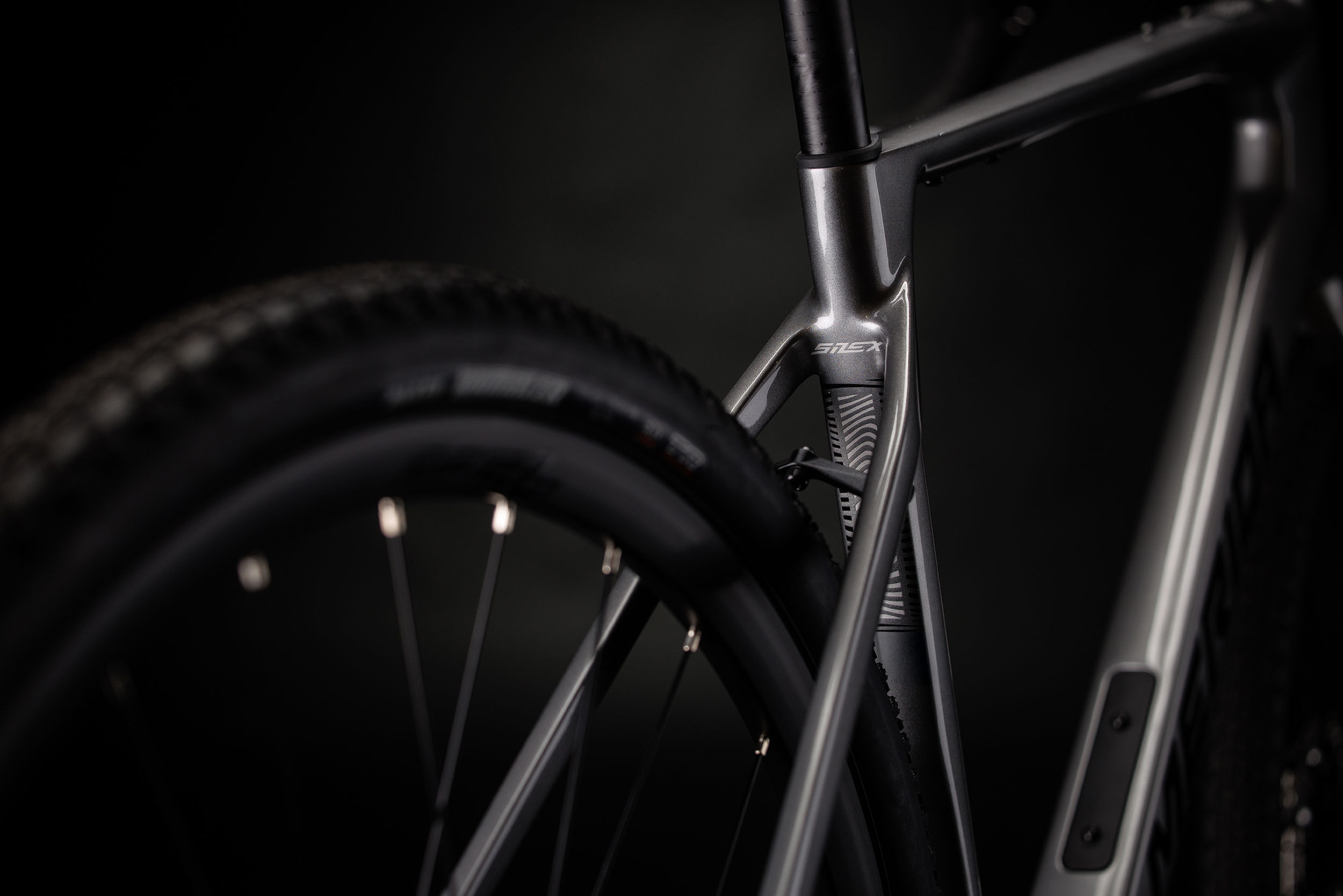 Close-up of a grey Merida gravel bike's rear wheel and frame on a dark background