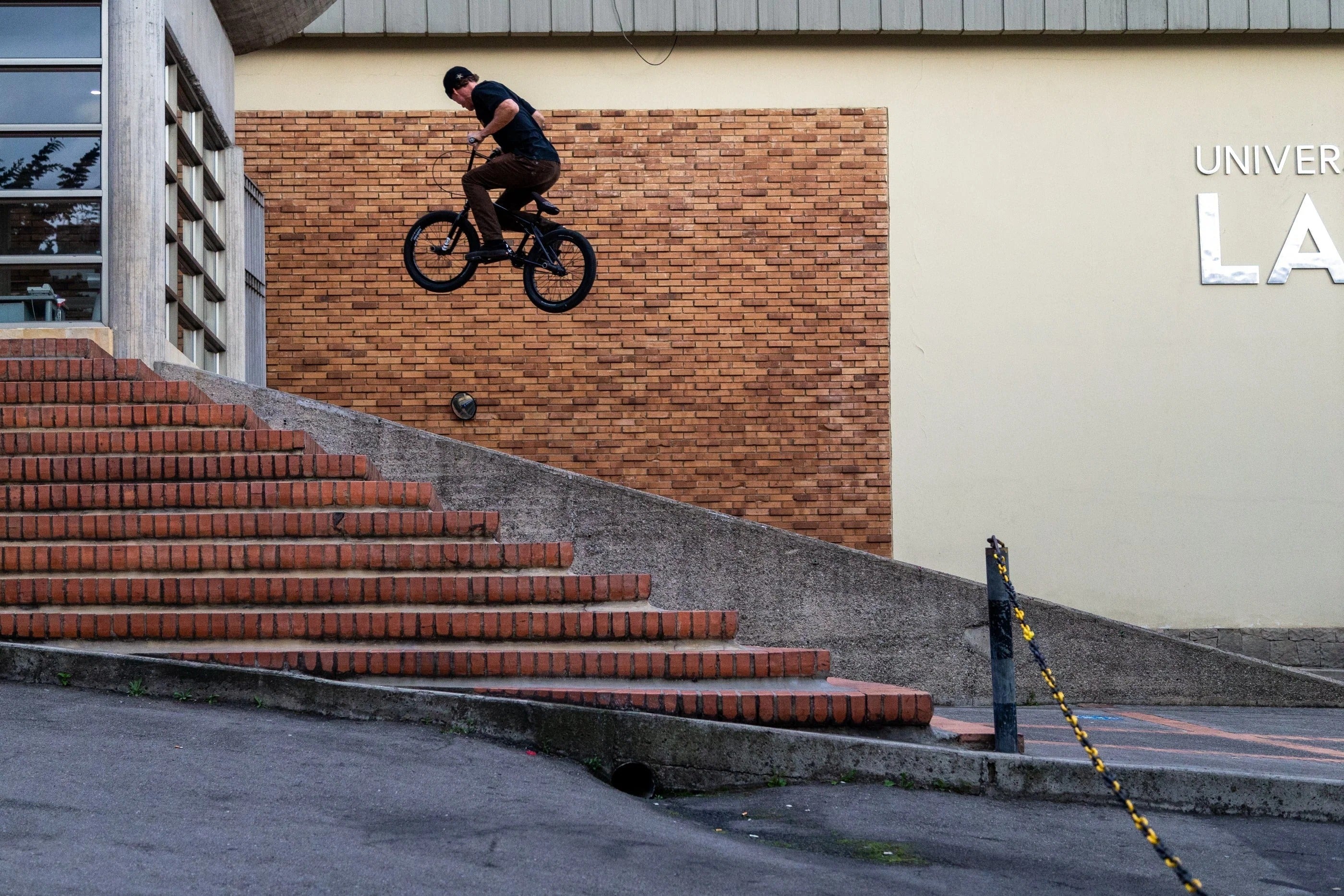 Person jumping a bmx bike on a staircase with a brick wall and building in the background
