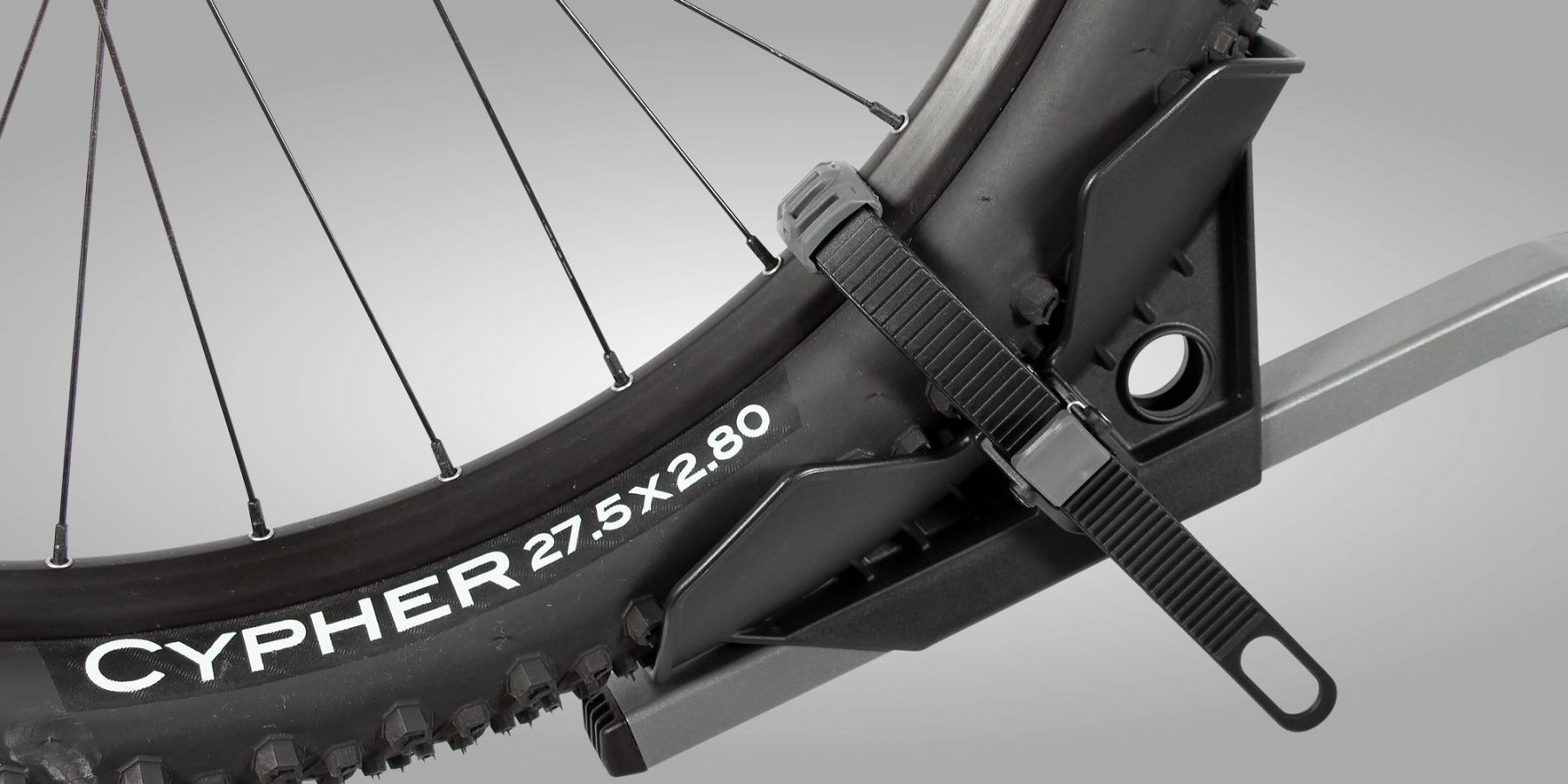 Close up of a bicycle wheel strapped into a bike rack on a gray background