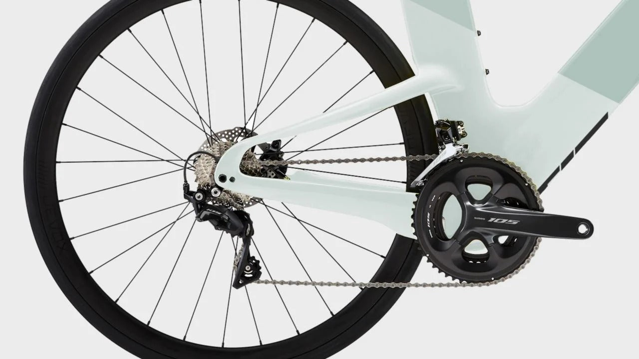 Close-up of a road bicycle's rear wheel and drivetrain, showing a black wheel, rear derailleur, chainring, and crankset on a clean white background.
