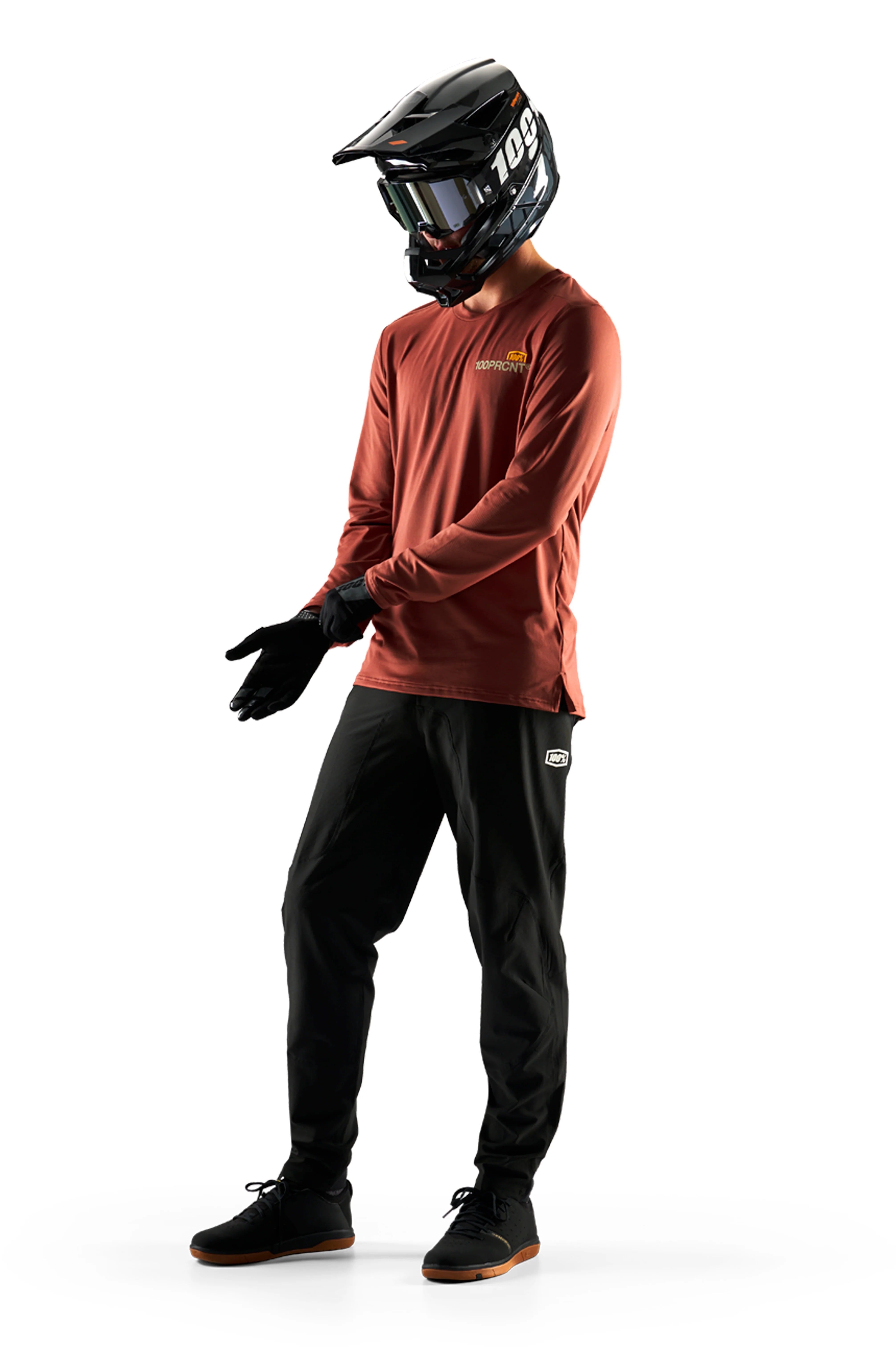 Person wearing a red long-sleeve shirt, black pants, gloves, and a full face helmet on a white background