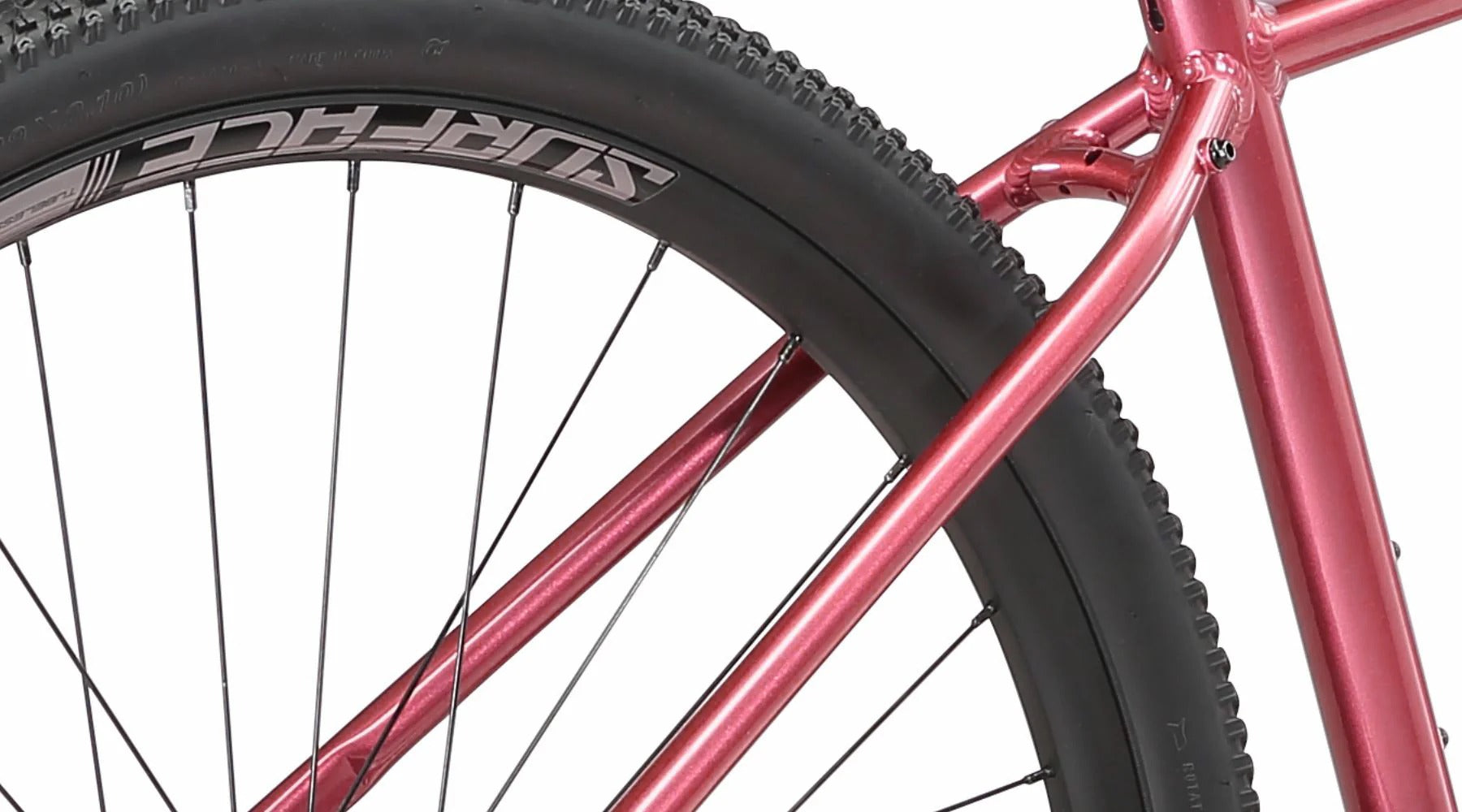 A close up of the rear wheel on a pinky red ladies mountain bike with a white background