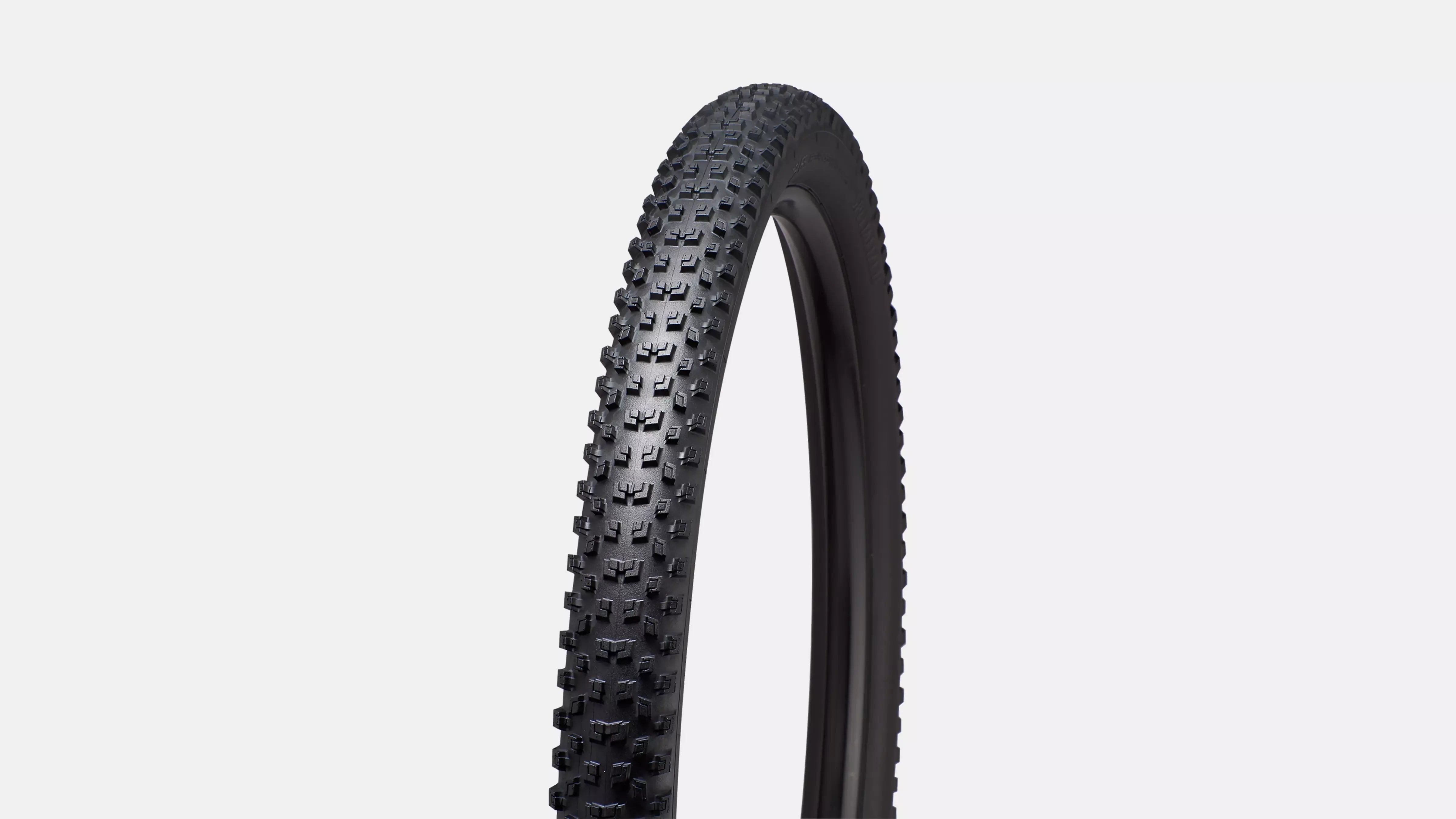 Black bicycle tyre with tread pattern on a light gray background