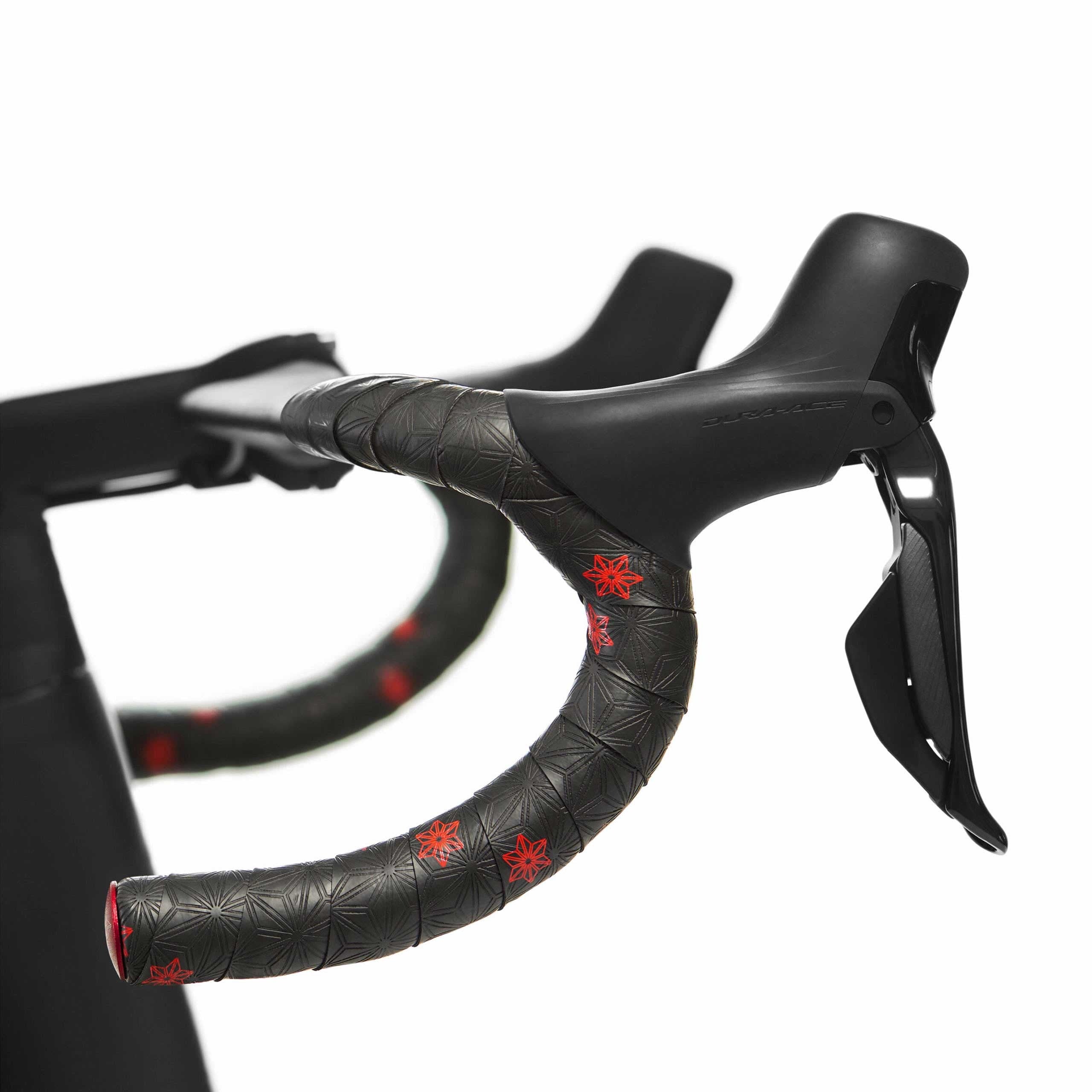 Close-up of a road bike handlebar with black bar tape with red stars on a white background