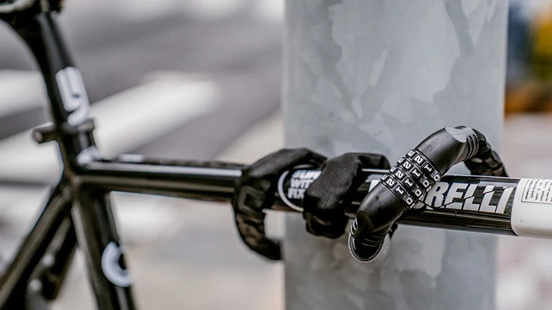 Bicycle with a black bike lock wrapped around the frame and a white pole on a blurred background