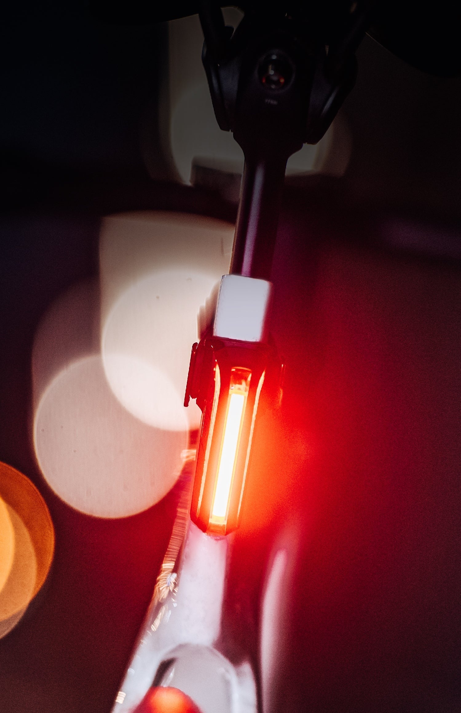 Close-up of a bicycle tail light with blurred lights in the background
