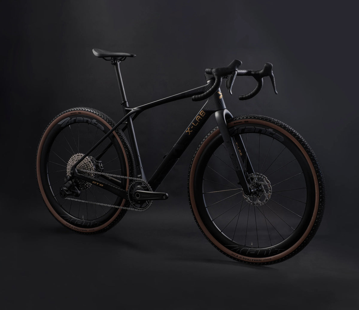 A matte black X-LAB gravel bicycle with gold branding on the frame, displayed on a dark studio background.