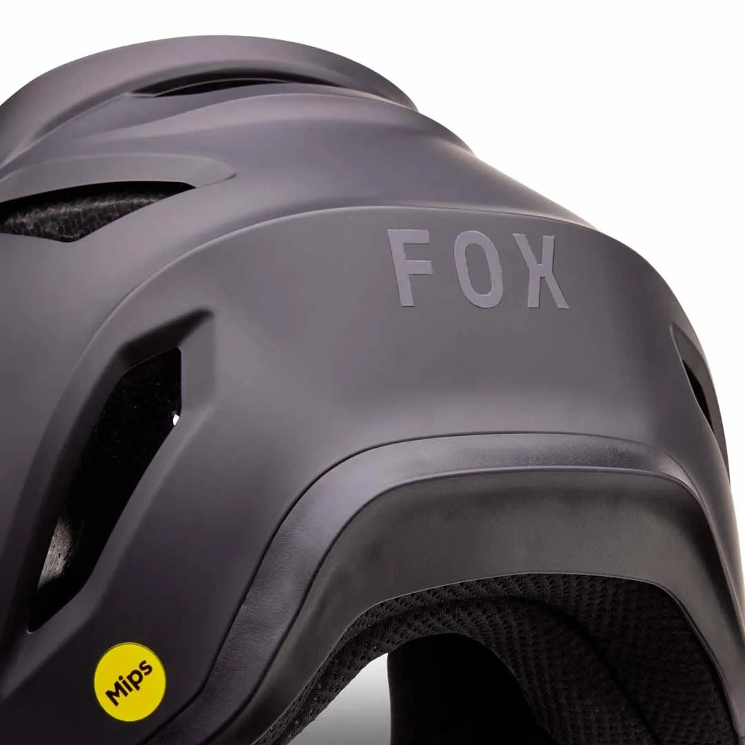 Close-up of a black Fox full face helmet with a yellow MIPS logo on a white background