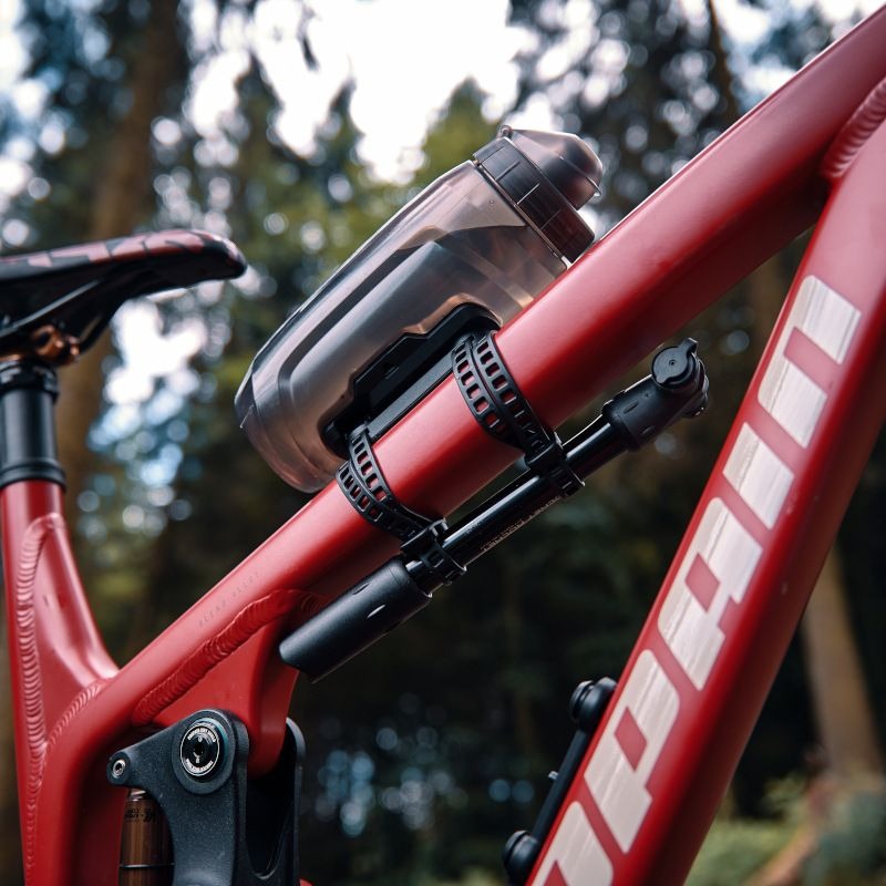 Red bicycle with a clear water bottle holder attached, outdoors.