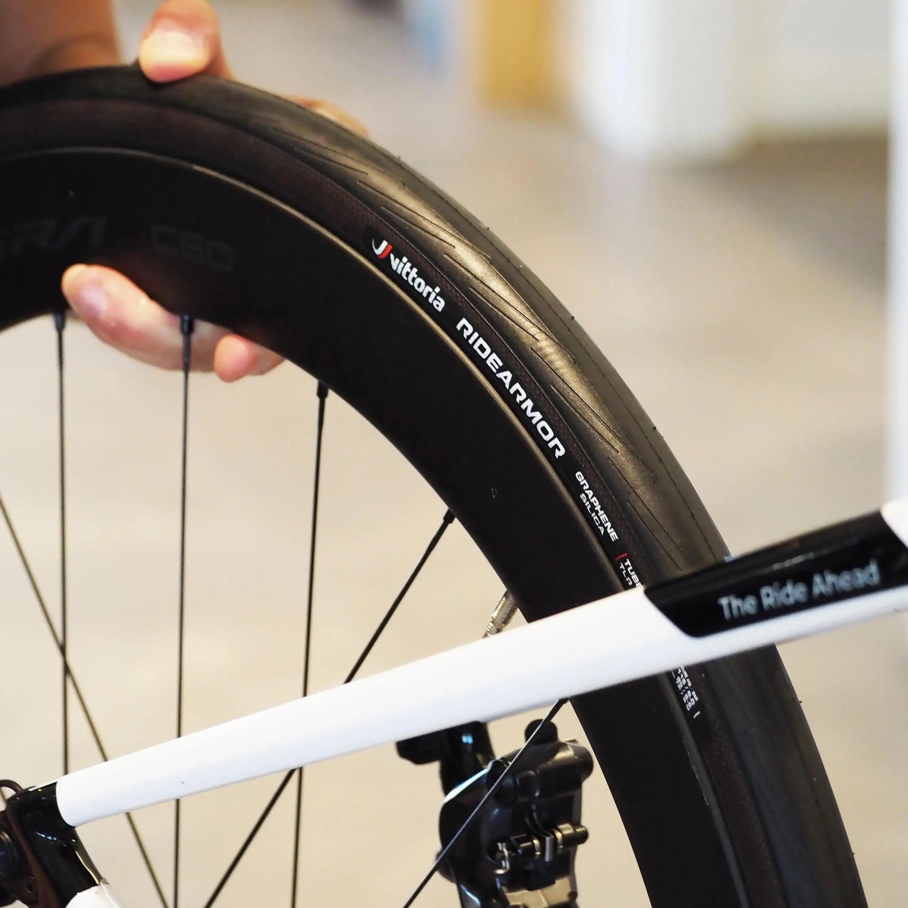 Bicycle tyre with Vittoria branding held by a hand against a blurred background