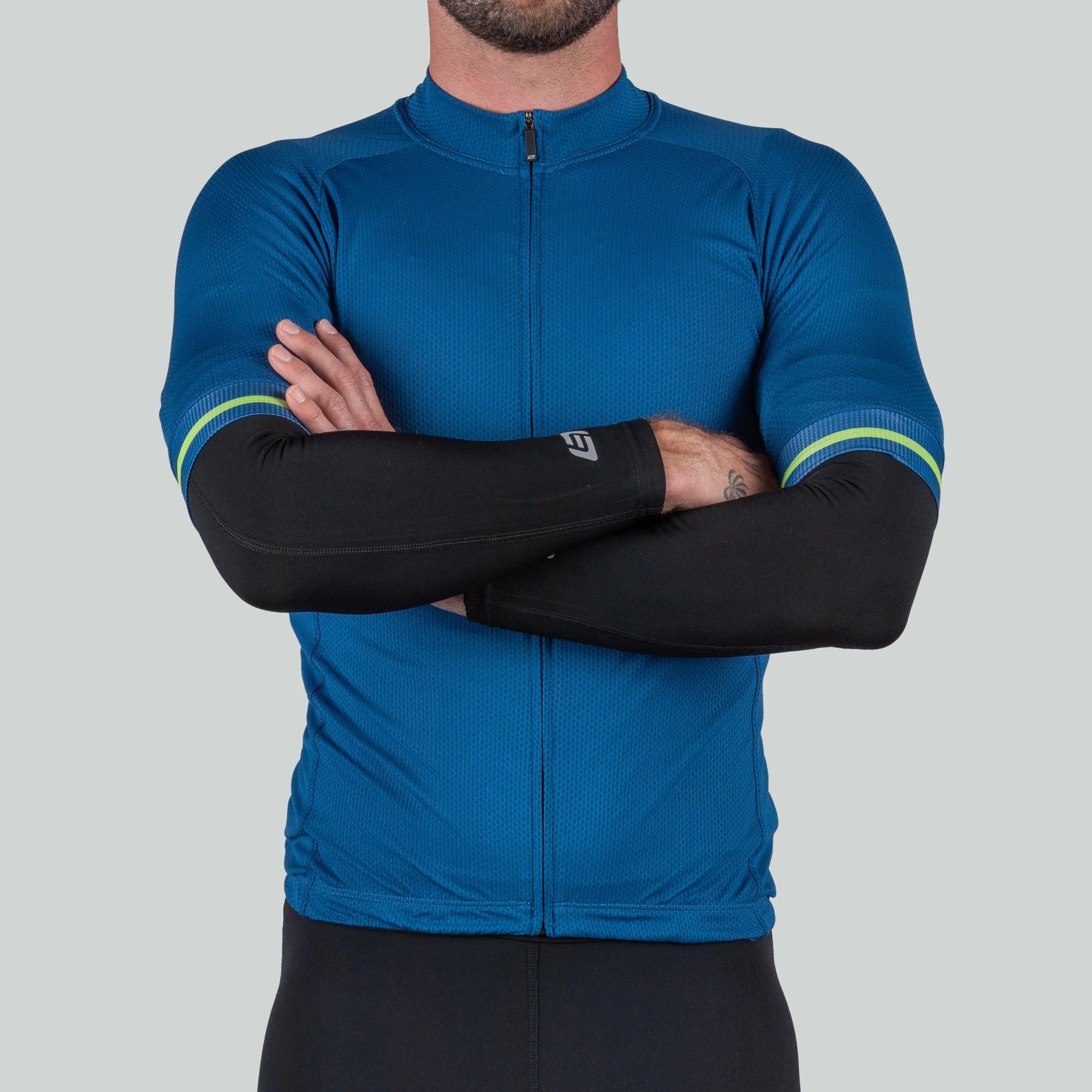 Person wearing a blue cycling jersey and black arm sleeves with green accents on a gray background