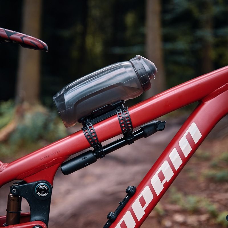 Bicycle water bottle holder on a red bicycle with a blurred forest background