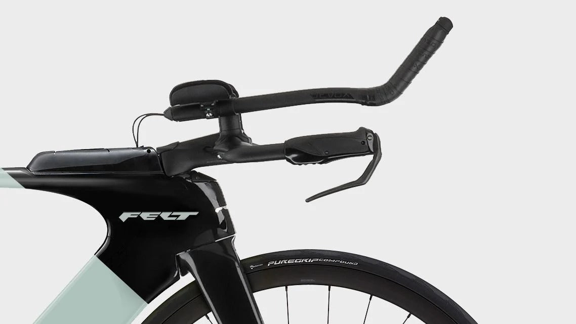 Close-up of a black Felt time trial bicycle handlebar and front fork with a pale mint green frame section, shown against a light gray studio background.