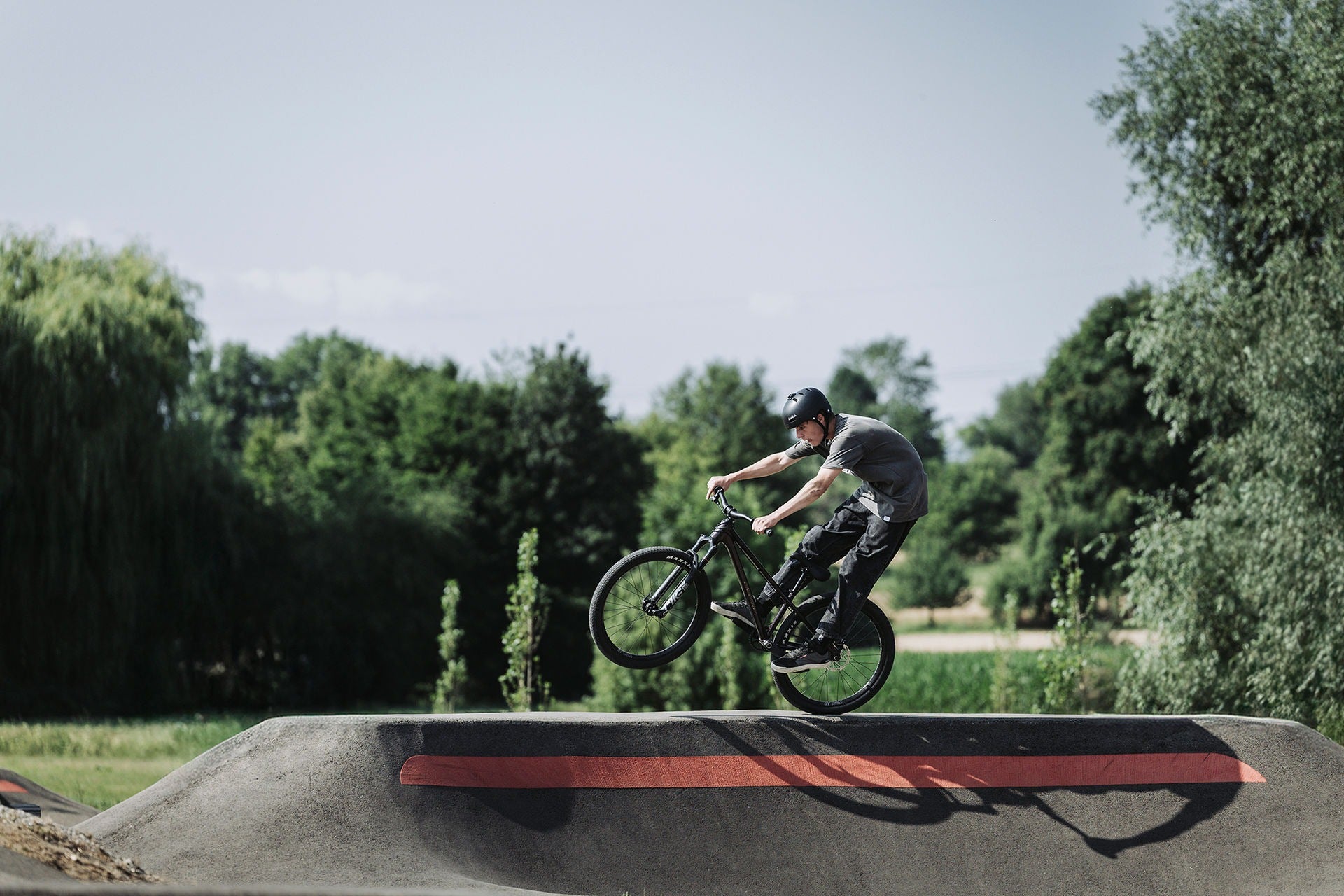 Person riding a bicycle on a concrete ramp with trees in the background