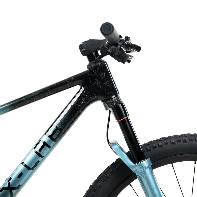 Close up of the front part of a blue and black X-LAB mountain bike frame and handlebar on a white background