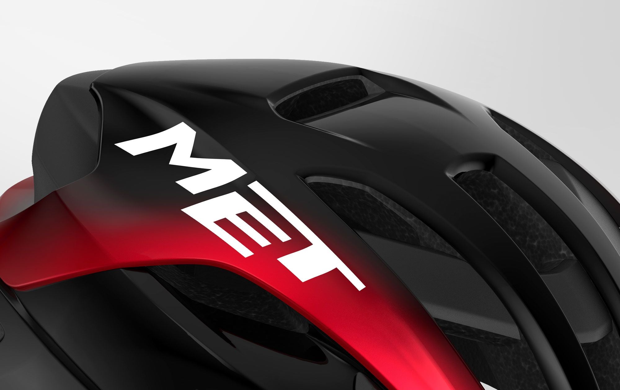 A close up picture of the Met Logo on the black and red Met Rivale II MIPS Road Helmet