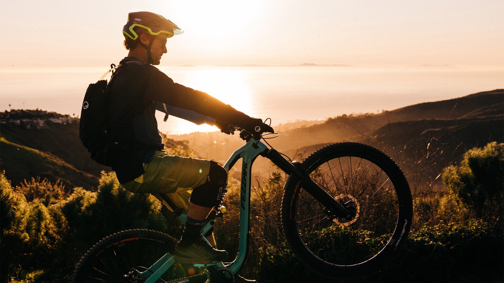 A picture of a guy doing a wheelie on a dual suspension mountain bike