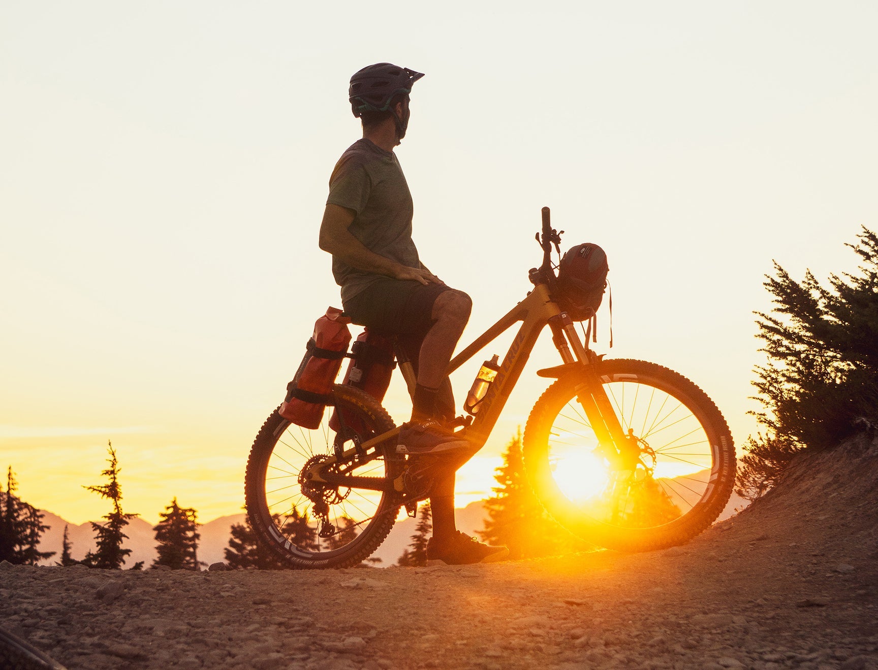 A picture of a silouette of a man at sunset on a mountain bike with the Aeroe Rear Bike Rack with cradles and bags